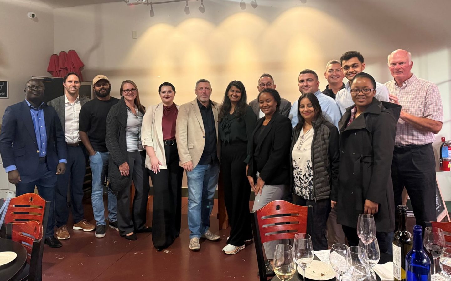 Galina Fendikevich standing with a group of attendees after a Council of Supply Chain Management Professionals event in a dining room, wearing a cream blazer over a burgundy top