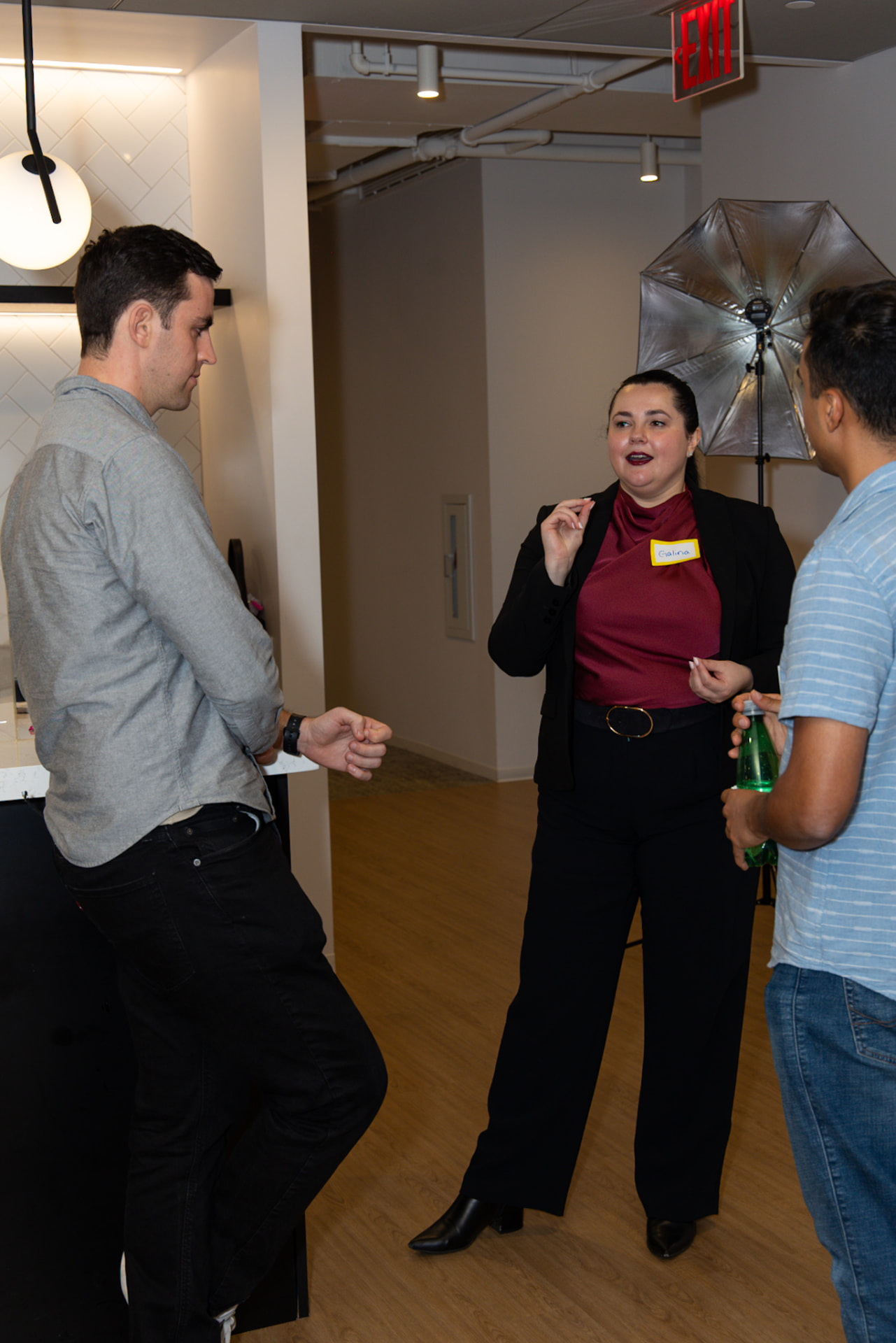 Galina Fendikevich standing and talking with two attendees in a lobby after the panel